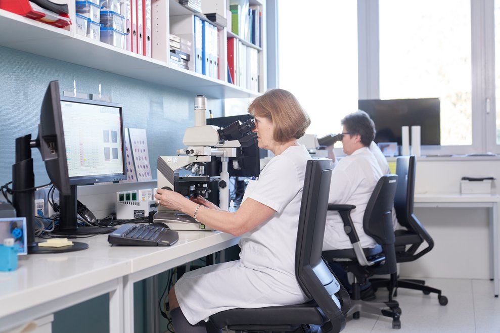 Analytikerin untersucht eine Laborprobe unter dem Mikroskop