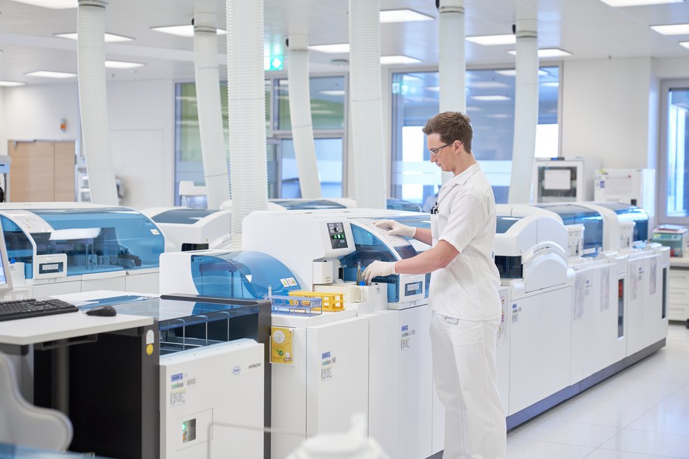 Labormitarbeiter lässt von einem Großgerät mehrere Laborproben überprüfen